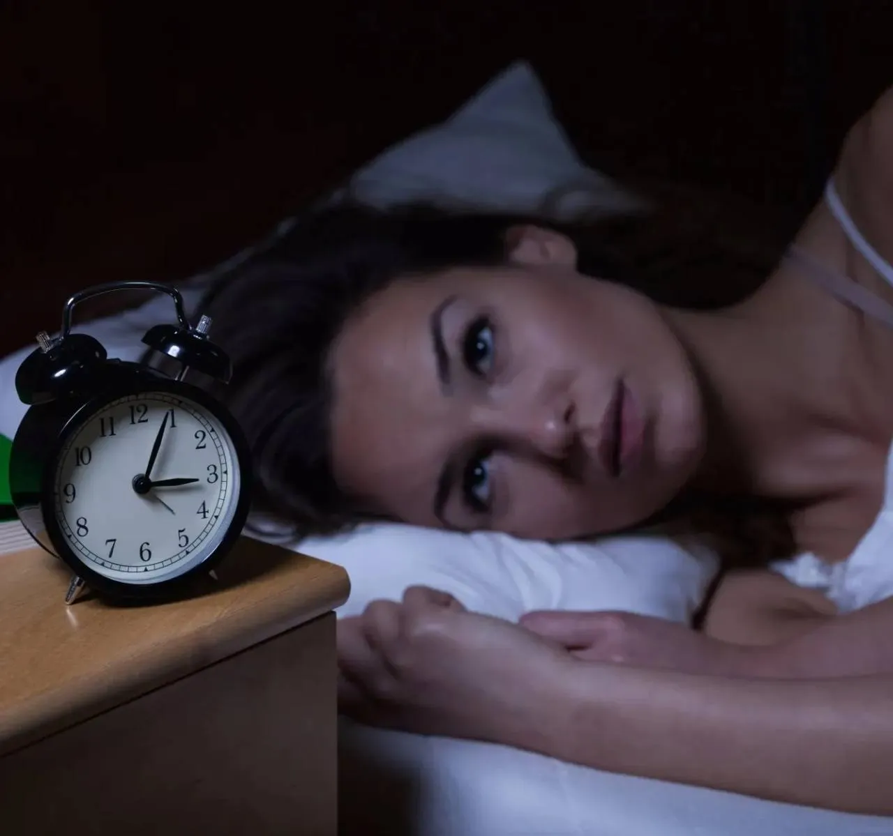 Femme éveillée pendant la nuit près d'un réveil